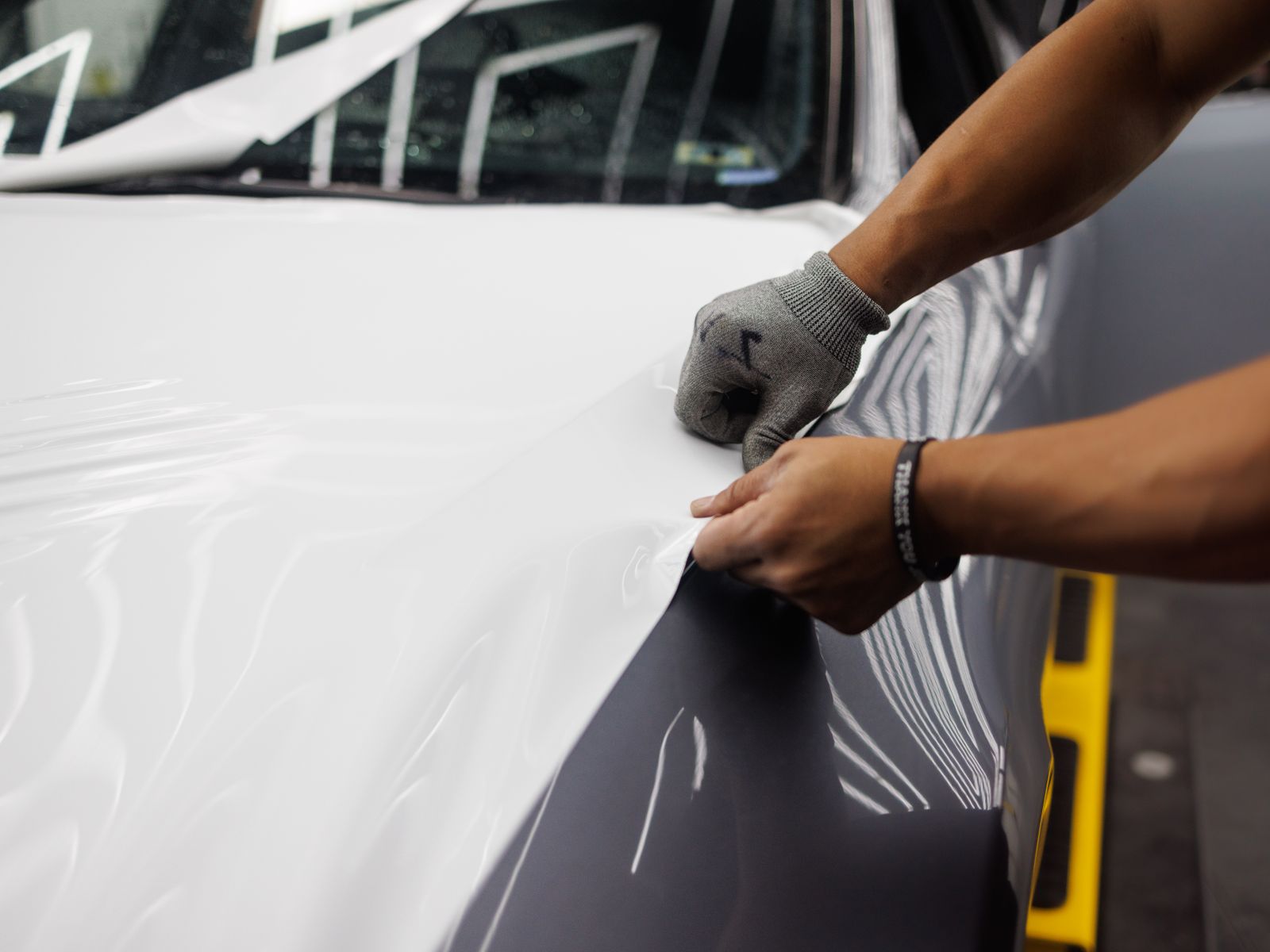 Close-up of an installer applying vinyl wrap to a car bonnet